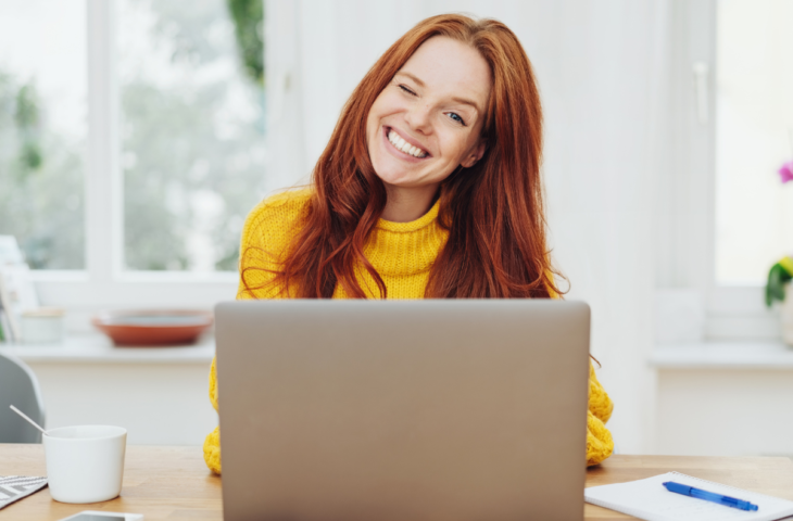 Enthousiaste vrouw achter een laptop, die gebruik maakt van het opleidingsbudget van haar werkgever.